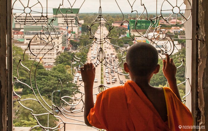 Un joven monje mirando la avenida Lane Xang desde el interior del arco del triunfo — Vientiane, Laos