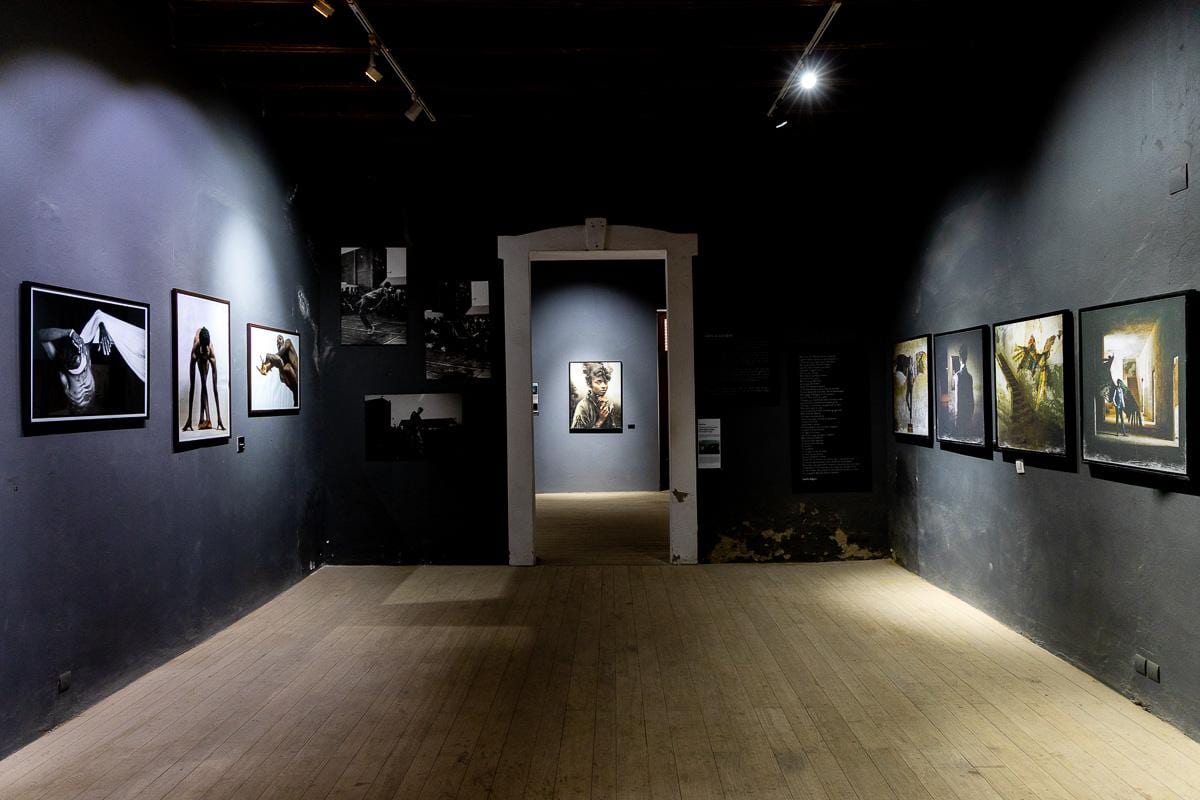 Sala de exposición del MuPho, con paredes negras y fotografías iluminadas con focos