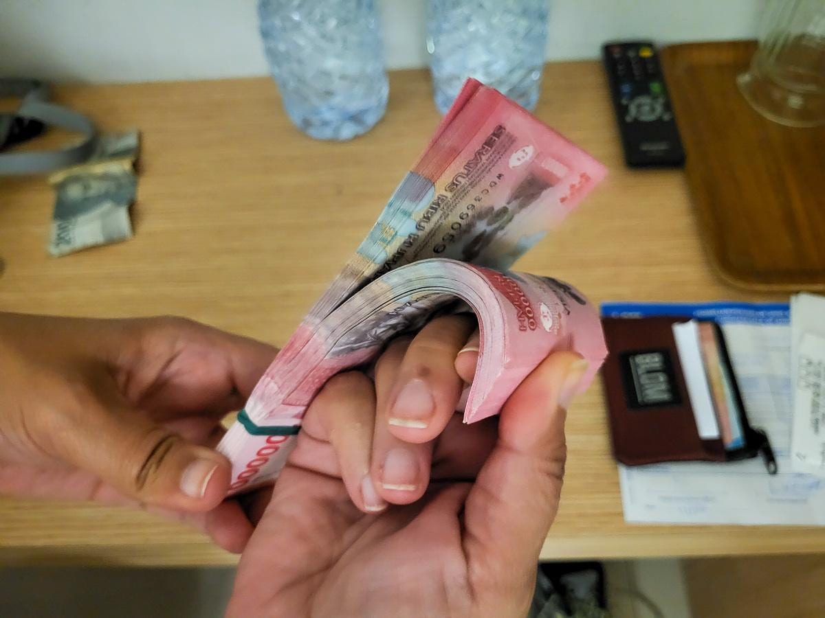 Un fajo de billetes de rupias indonesias cambiando de manos tras el cambio en el banco