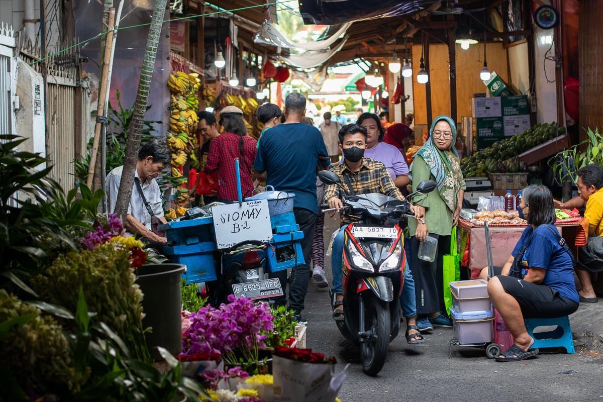 Un callejón de mercado de Yakarta, con las motos abriéndose paso entre los puestos de fruta y flores