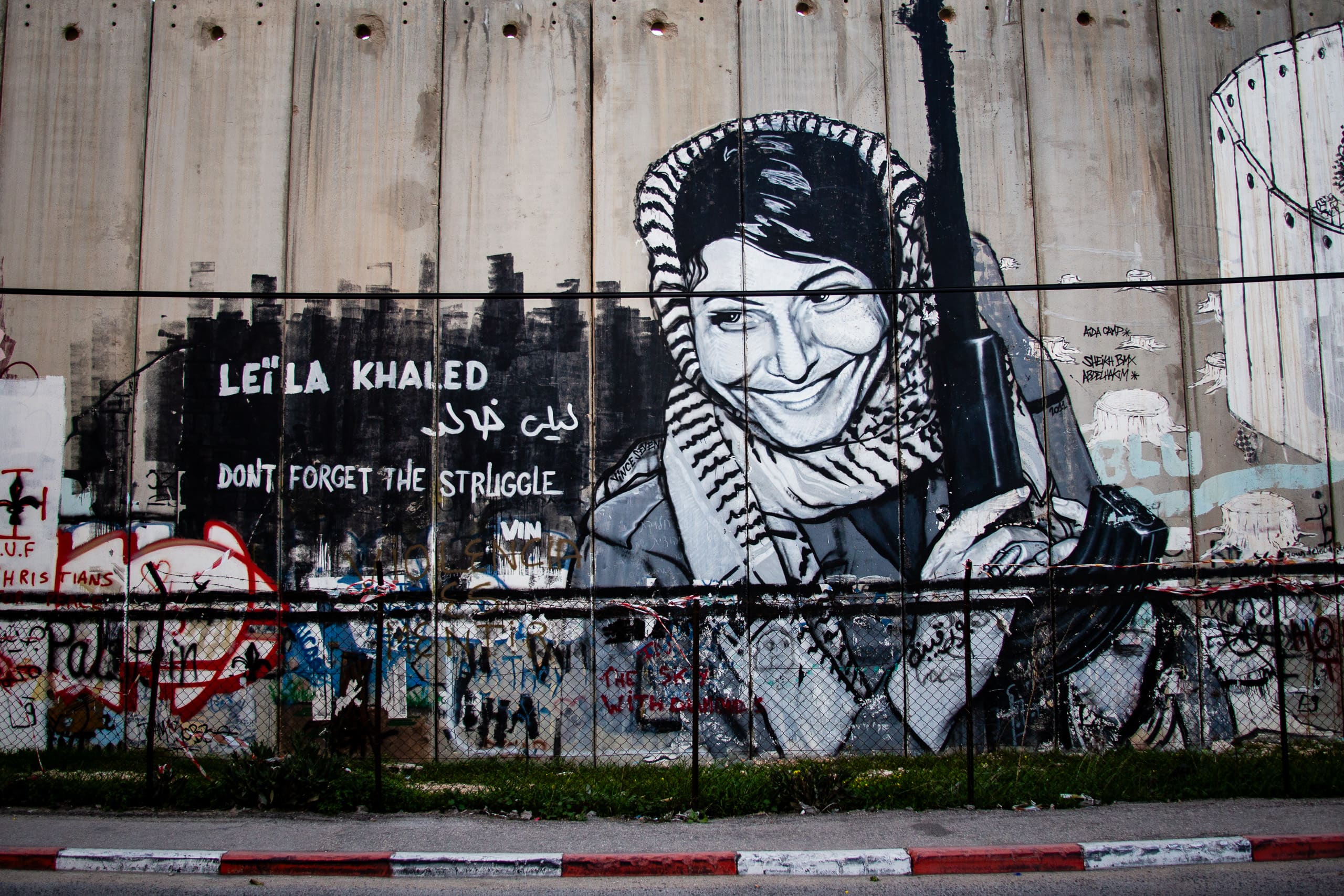 Mural de Leila Khaled en el muro de separación de Belén, en Palestina, con la frase Don't forget the struggle
